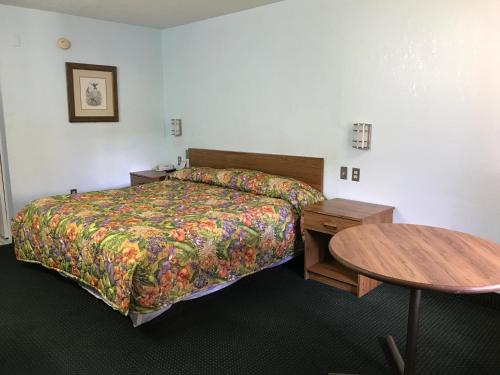 キシミーにあるフラミンゴ インのベッドとテーブルが備わるホテルルームです。