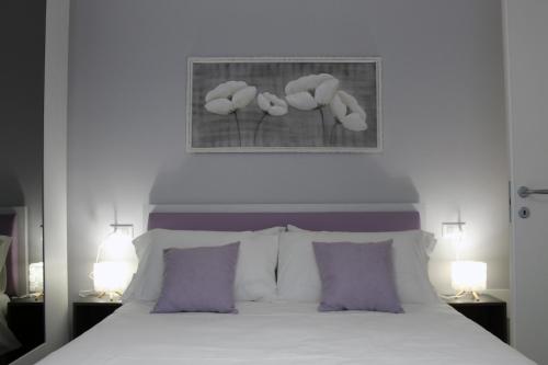 een slaapkamer met een wit bed met paarse kussens bij Abelia 4 in Pietra Ligure