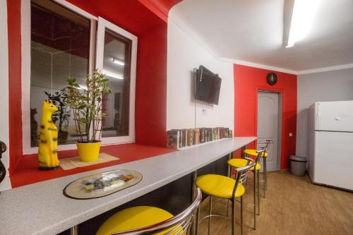 a kitchen with yellow and red walls and a counter with yellow stools at Cool Traveler in Kyiv