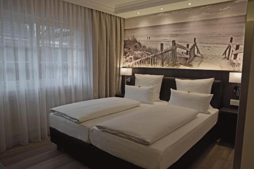 una camera con un letto e una foto di una spiaggia di Fisher's Inn a Zingst