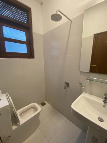 a white bathroom with a sink and a toilet at Arches Fort in Galle