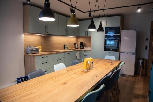 a kitchen with a wooden table and blue chairs at Roomie Alps Design Hostel in Kitzbühel