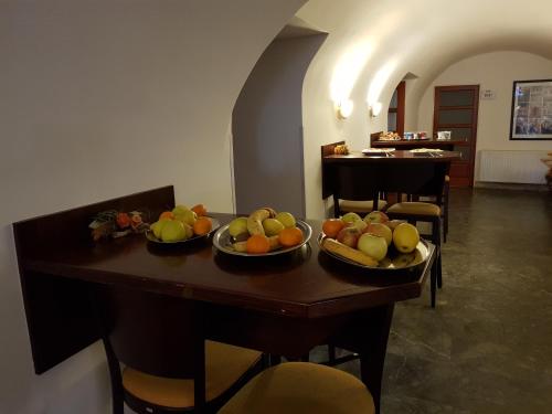 a table with bowls of fruit on top of it at Městský Hotel Dorinka in Hostinné