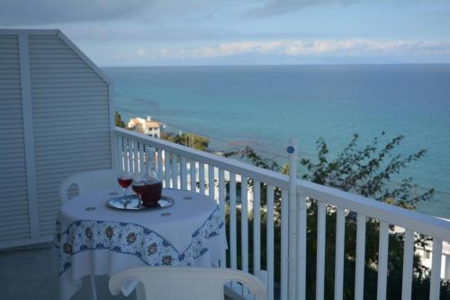 a table with a glass of wine on a balcony at FIORE ROOMS in Akrotiri