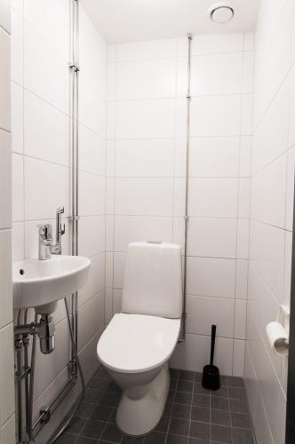 a white bathroom with a toilet and a sink at Aikatalo Hostel Helsinki in Helsinki