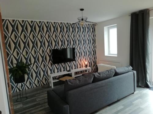sala de estar con sofá y pared geométrica en La Petite Pause en Verlinghem