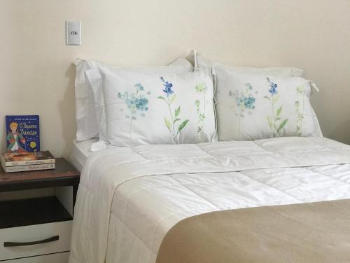 a bed with white sheets and blue and white pillows at Aconchego próximo à Cascanéia e Blumenau in Gaspar