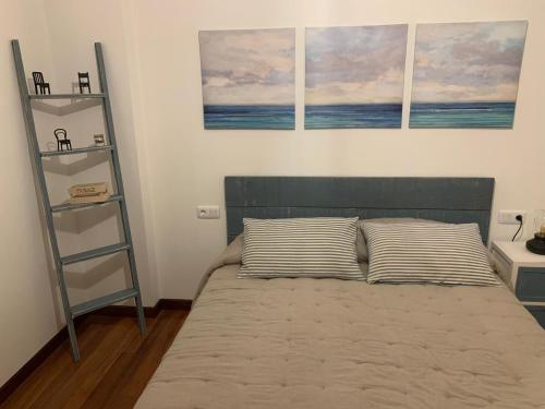 a bedroom with a bed with two pillows and two shelves at Casa Mar y Sol in Corcubión