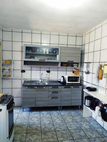 een keuken met een wastafel en een magnetron bij Casa de Pessoas Felizes! in Florianópolis