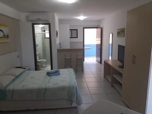 1 dormitorio con 1 cama y TV y cocina en Marsallis Elegance Flat, en Natal