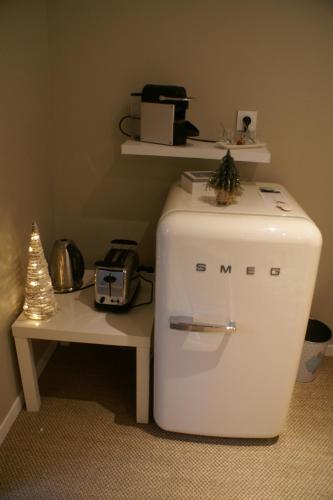 a small white refrigerator sitting next to a table at Magnifique Suite avec Jacuzzi privatif in Martragny
