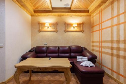 a living room with a leather couch and a table at Ganz SKI Lift 5 in Bukovel