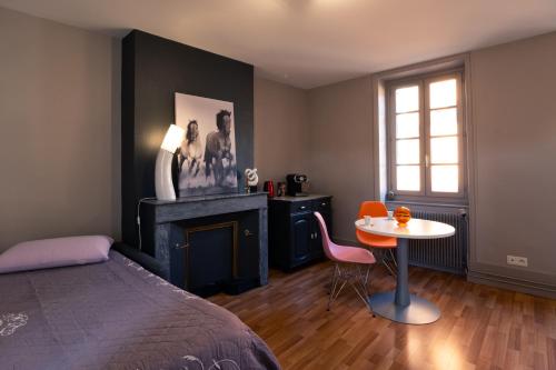 a bedroom with a bed and a table and a fireplace at Les Orchidées in Cluny