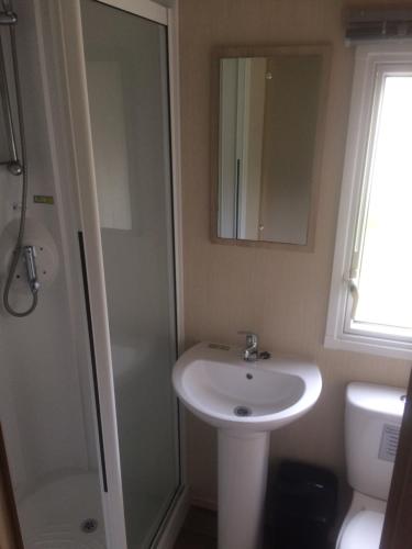 a bathroom with a sink and a shower and a mirror at Isle of Wight Caravan in Shanklin