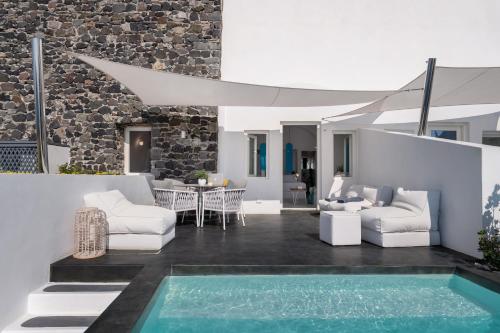 a patio with white furniture and a swimming pool at Marizan Caves & Villas in Oia