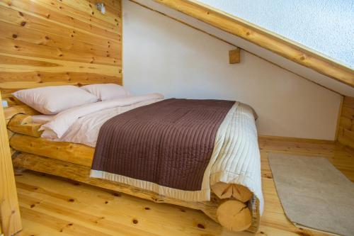 a bed in a room with a wooden wall at Durmitorske zore in Žabljak