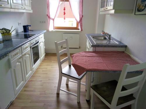 uma cozinha com uma mesa, um lavatório, uma mesa e cadeiras em Ferienwohnung Familie Schneider em Neustadt in Sachsen