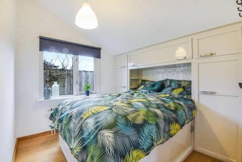 a bedroom with a large bed with a tropical print at Tinyhouse Dirkshorn Noord-Holland honden welkom omheinde tuin 10 km van strand in Dirkshorn