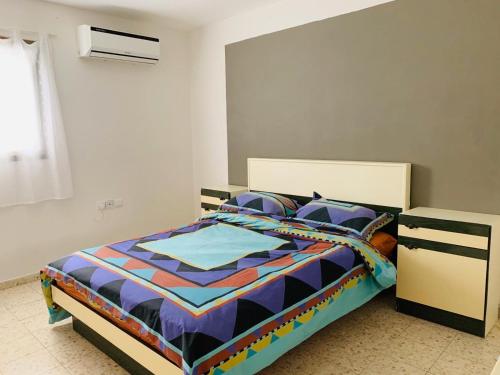 a bed with a colorful comforter in a bedroom at Tamar's House in Arad
