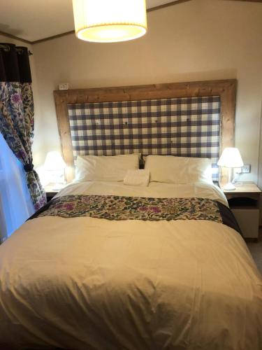 a bedroom with a large bed with a large headboard at 81 The Heathers, Aviemore Holiday Park , Dalfaber rd Aviemore PH22 1PX in Aviemore