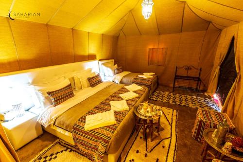 a bedroom with two beds in a tent at Sahara Merzouga Luxury Camp in Merzouga