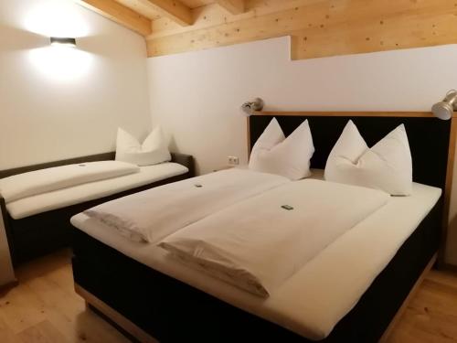 um quarto com uma cama grande com lençóis brancos e almofadas em Studler Hofchalets em Oberperfuss