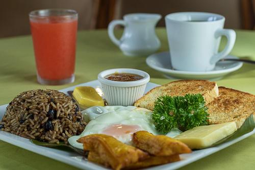 a plate of food with eggs meat and bread on a table at Hotel Playa Bejuco in Esterillos Este