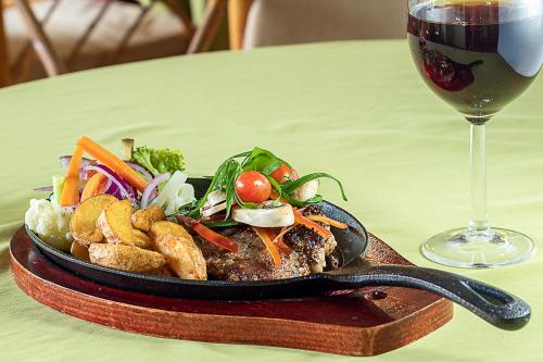 a plate of food on a table next to a glass of wine at Hotel Playa Bejuco in Esterillos Este