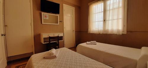 a hotel room with two beds and a window at Hotel Rivadavia in Piriápolis