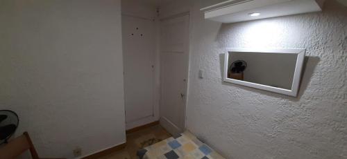 a room with a white wall with a television on it at Hotel Rivadavia in Piriápolis