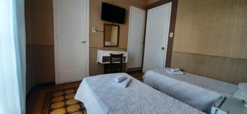 a hotel room with two beds and a television at Hotel Rivadavia in Piriápolis