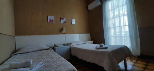 a room with two beds and a window at Hotel Rivadavia in Piriápolis