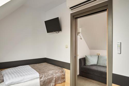 a bedroom with a bed and a couch and a mirror at Gold House Pension in Balatonfüred