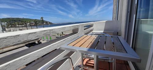 a bench on a balcony with a view of the ocean at Hotel Rivadavia in Piriápolis