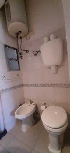 a white bathroom with a toilet and a sink at Hotel Rivadavia in Piriápolis