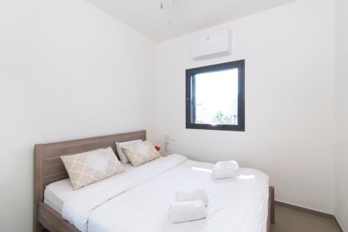 a bedroom with a bed with white sheets and a window at Hilton Bay Apartment with Bedroom shelter in Tel Aviv