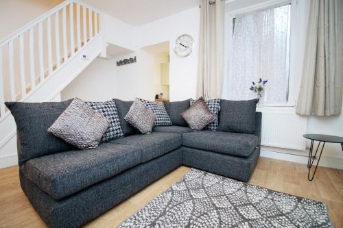 a living room with a gray couch and a staircase at Spacious 4BR Home Near Swansea Sleeps 8 in Swansea