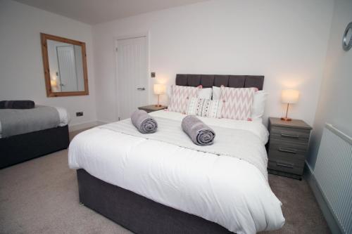 a bedroom with a large white bed with two pillows at Spacious 4BR Home Near Swansea Sleeps 8 in Swansea