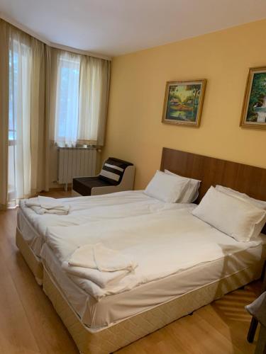 a bedroom with a large white bed and a chair at Studios -Villa Park SV in Borovets