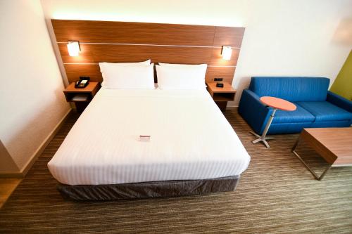 a hotel room with a bed and a blue chair at Holiday Inn Express Hotel & Suites Port Clinton-Catawba Island by IHG in Port Clinton