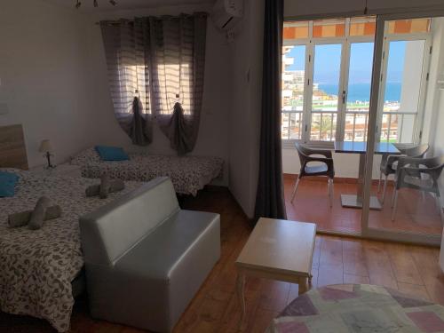 a room with two beds and a living room with a balcony at Palm Beach 8th - La Carihuela in Torremolinos