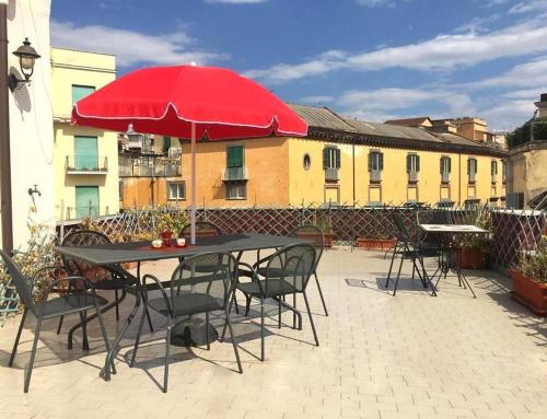 ナポリにあるPanoramico con terrazzoのパティオ(赤い傘付きのテーブルと椅子付)