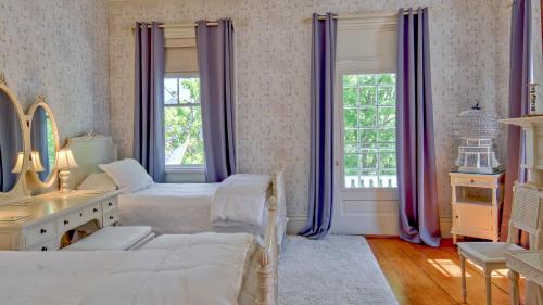 a bedroom with two beds and a mirror and purple curtains at Captain Morse House - Luxury, Waterfront, Town, & Beaches - 5 stars in Edgartown