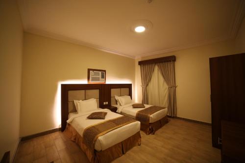 een hotelkamer met 2 bedden en een raam bij ريف قباء للشقق الفندقيه in Al Madinah
