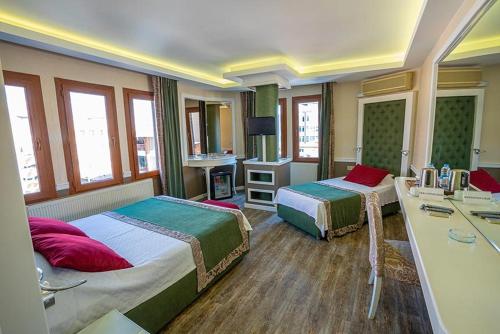 a hotel room with two beds and a desk at Berrak Otel in Salihli