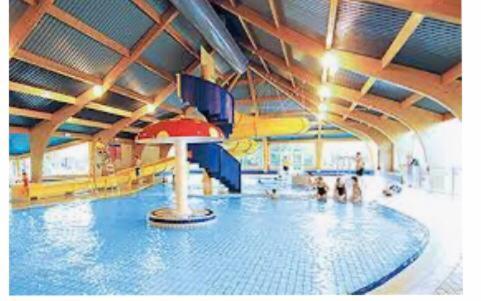 a swimming pool with a slide in a large room at Waters Edge in Cirencester