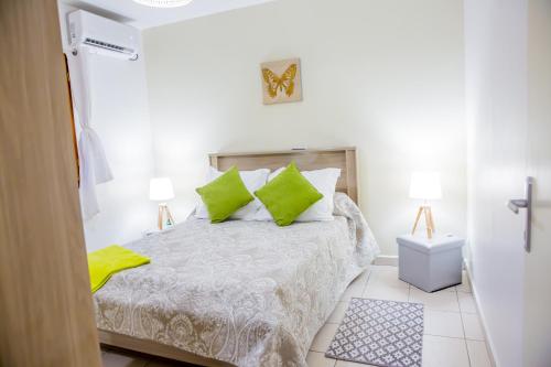 a white bedroom with a bed with green pillows at Villa A rabica - Extrait de Café in Pointe-Noire