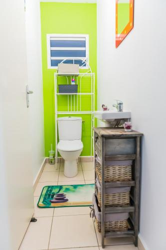 a bathroom with a toilet and a green wall at Villa A rabica - Extrait de Café in Pointe-Noire