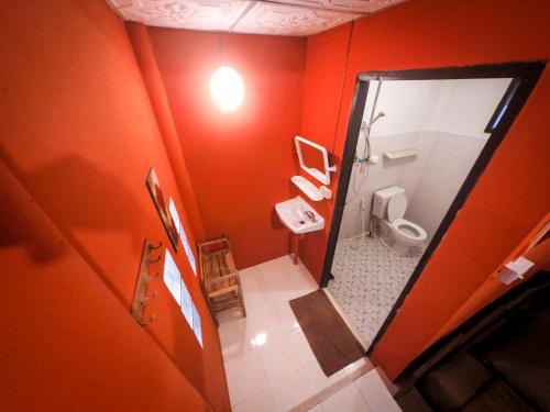 Baño de color naranja con aseo y espejo en Chilling Hill Guesthouse, en Pai