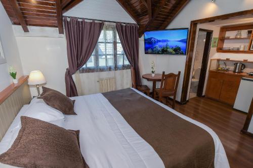 a bedroom with a large bed and a television at Apart & Hotel La Fontaine - by ROTUI in San Martín de los Andes